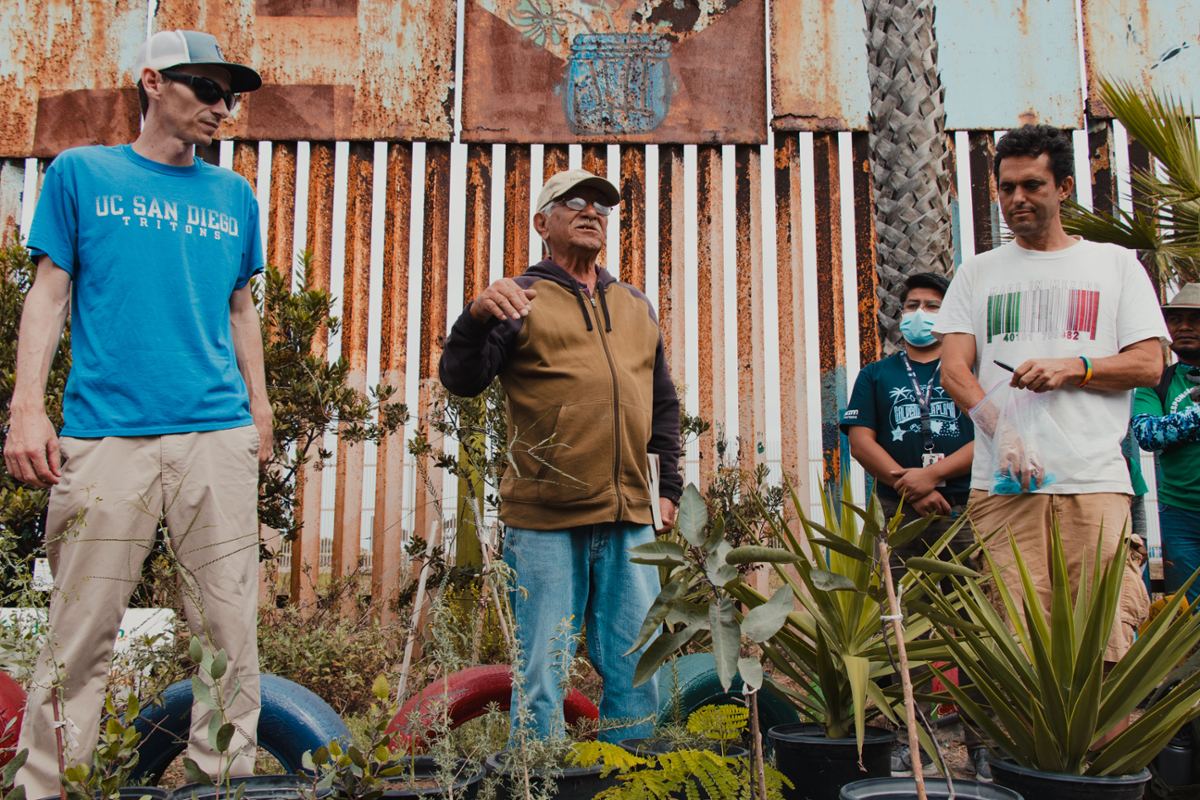 Three men standing by fence